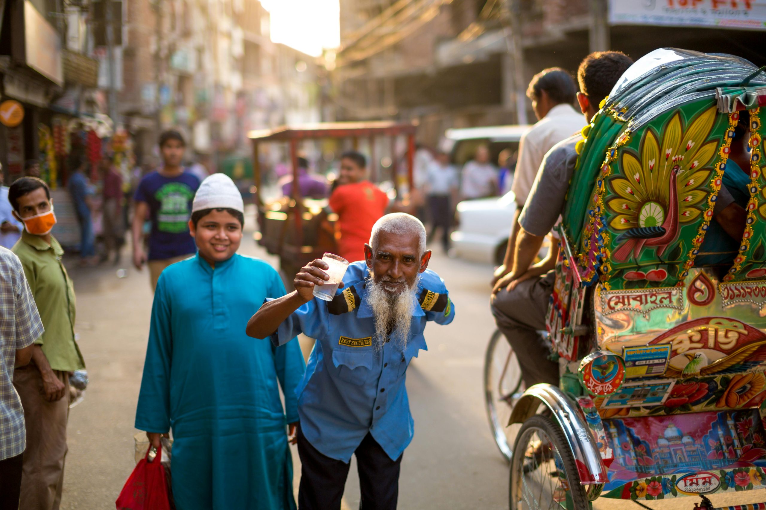 A lively street in Bangladesh with people, colorful rickshaws, and a friendly atmosphere.